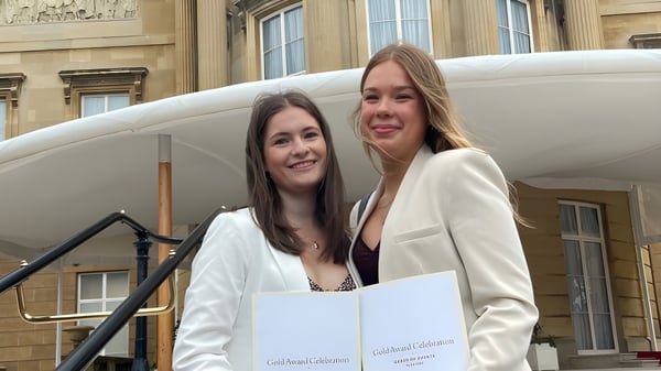 Zwei Schülerinnen stehen lächelnd vor einem historischen Gebäude auf dem Campus des St. Francis' College.