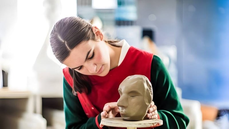 Ein Schüler des St. Francis' College formt konzentriert eine Tonfigur in einem Atelier.
