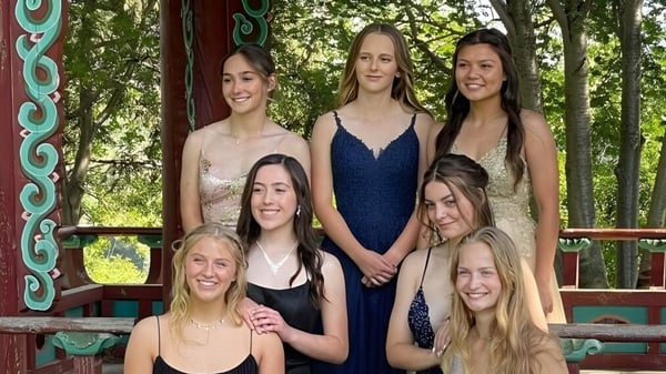 Eine Gruppe junger Schülerinnen steht auf einem Holzdeck vor einer farbenfrohen Struktur auf dem Gelände der St. Francis Xavier High School.