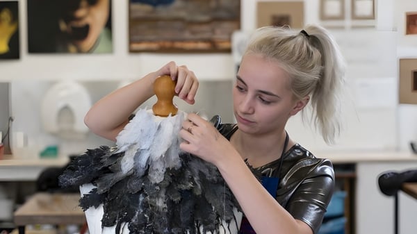 Eine Schülerin der St. George's School Edinburgh untersucht ein gefiedertes Kostümstück im Kunststudio.