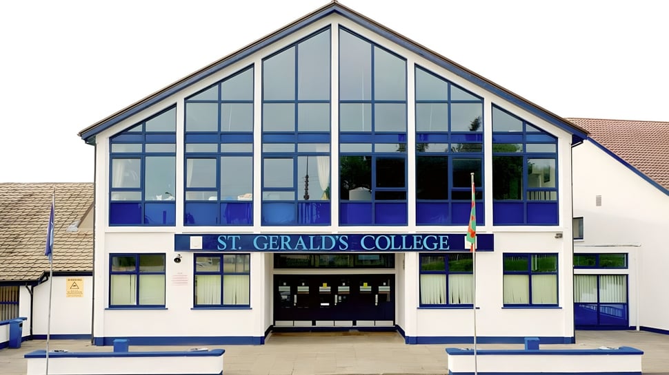 Das moderne Glasgebäude mit der Aufschrift St. Gerald's College ist von einem gepflasterten Bereich umgeben.