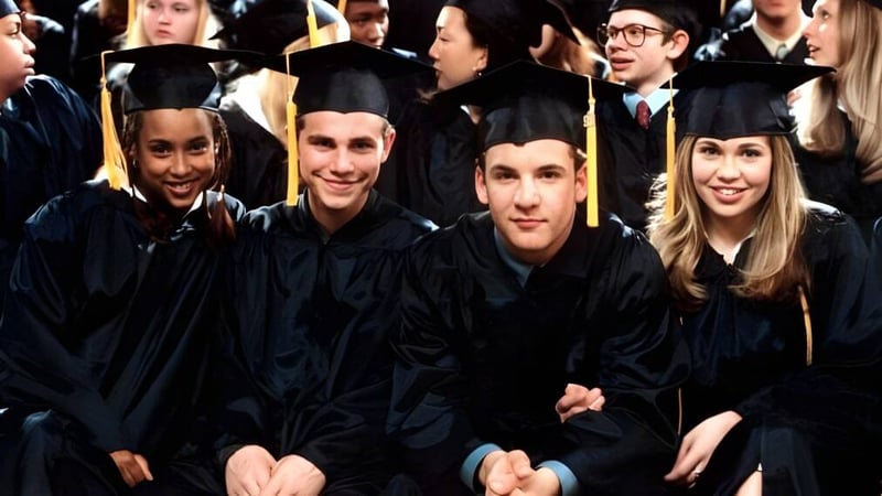 Eine Gruppe Absolventinnen und Absolventen in schwarzen Talaren feiert ihren Abschluss am St. Gerald's College.