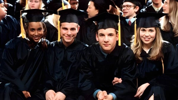 Eine Gruppe Absolventinnen und Absolventen in schwarzen Talaren feiert ihren Abschluss am St. Gerald's College.