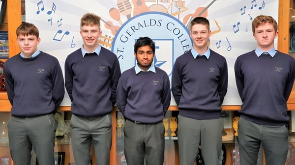 Fünf Schüler in Schuluniform stehen vor einer Kulisse mit dem Namen St. Gerald's College und Musiknoten.