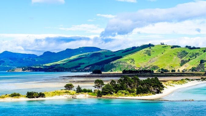 Ein malerisches Küstenlandschaftsbild mit grünen Hügeln und einem blauen Gewässer nahe der St. Hilda's Collegiate School.