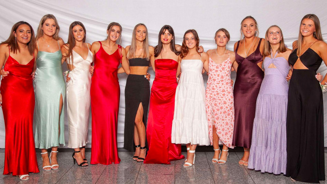Eine Gruppe junger Frauen in bunten Abendkleidern posiert auf einem weißen Hintergrund am St. Hilda's Collegiate School.