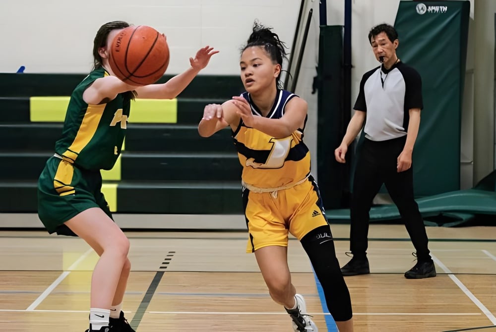 Zwei Basketballspieler in gelben und grünen Trikots kämpfen um den Ball auf dem Spielfeld der St. James Collegiate.
