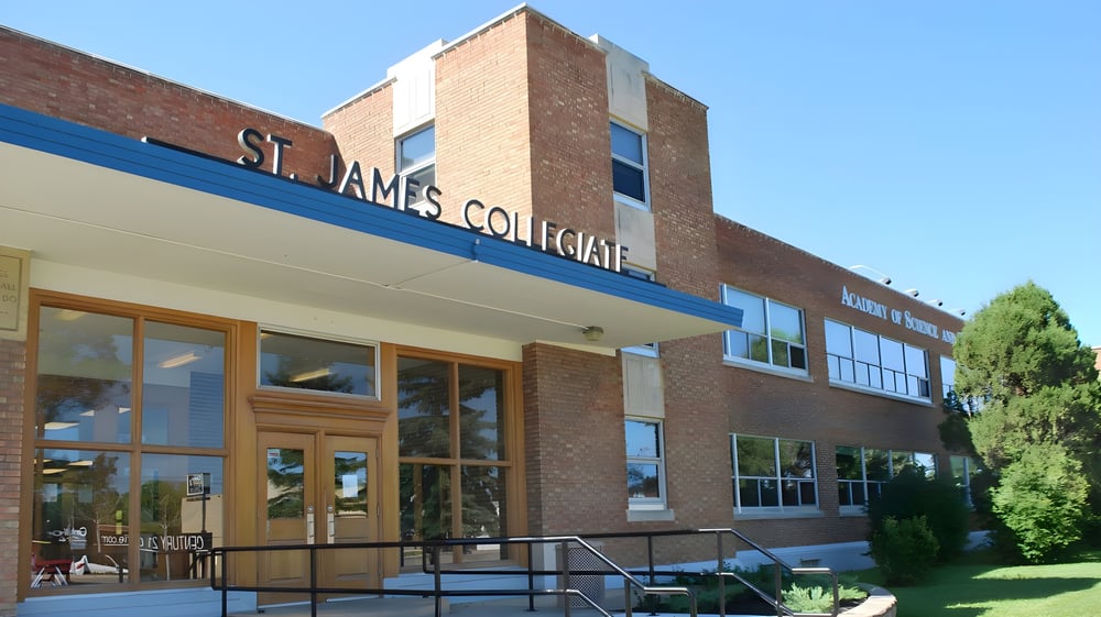 Das Backsteingebäude der St. James Collegiate ist von Bäumen und einer Rasenfläche umgeben.