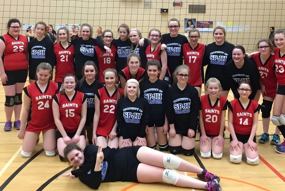 Die Mädchen-Basketballmannschaft der St. James' Regional High steht gemeinsam auf dem Basketballfeld in roten und schwarzen Trikots.