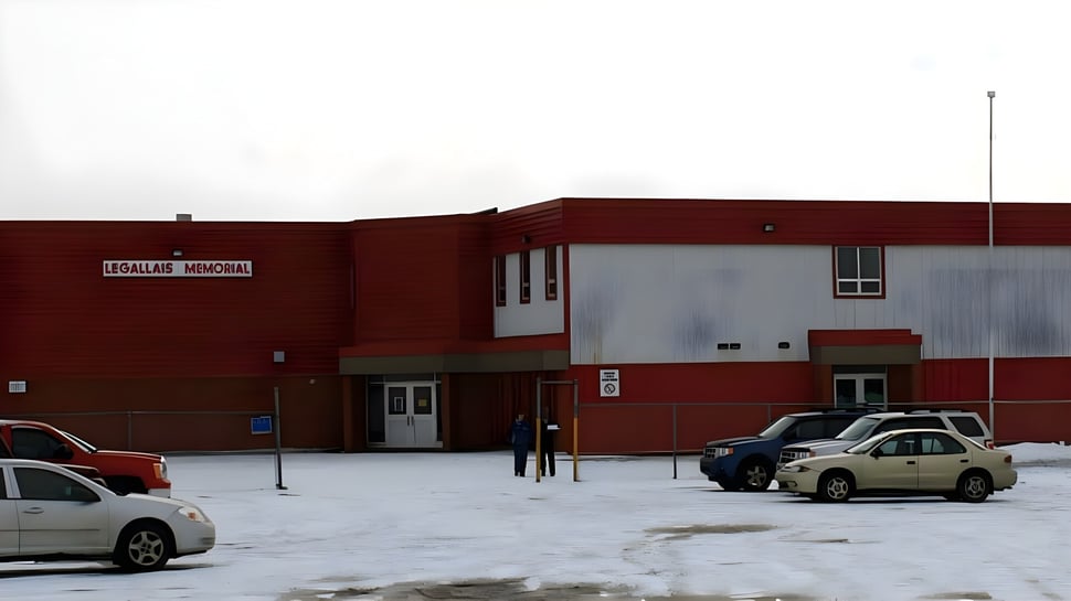 Das rote Backsteingebäude der St. James' Regional High steht vor einem verschneiten Parkplatz mit geparkten Fahrzeugen.