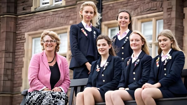 Eine Gruppe von Schülerinnen der St. James’ School steht vor einem Backsteingebäude.