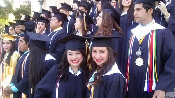 Eine Gruppe von Absolventinnen und Absolventen der St. John Paul II High School steht im Freien in akademischer Kleidung und lächelt in die Kamera.