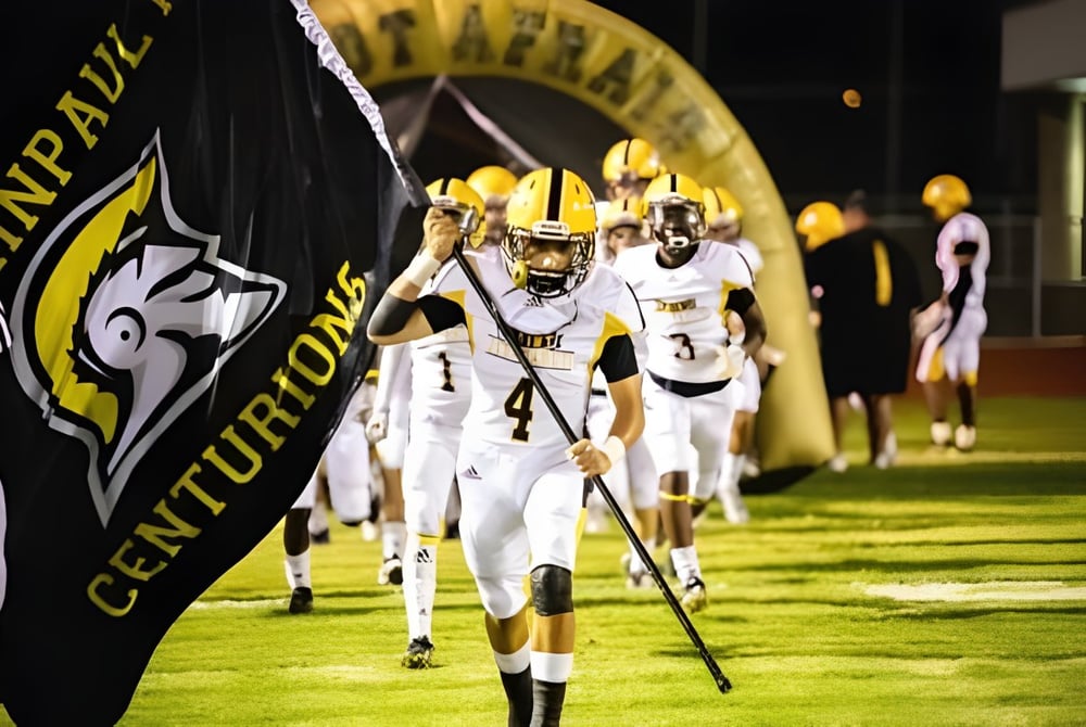 Schüler der St. John Paul II High School gehen in weißen Trikots auf das Fußballfeld.