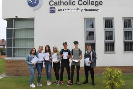 Eine Gruppe von Schülerinnen und Schülern steht mit Zertifikaten vor dem Gebäude des St. John Plessington Catholic College.