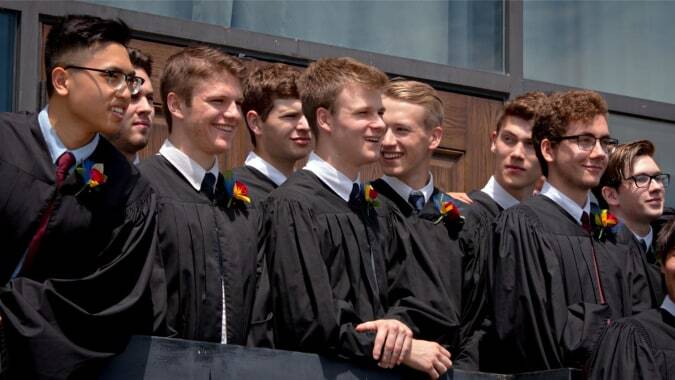 Eine Gruppe von Schülern der St. John’s-Kilmarnock School steht in Abschlussgewändern vor einem Gebäude.