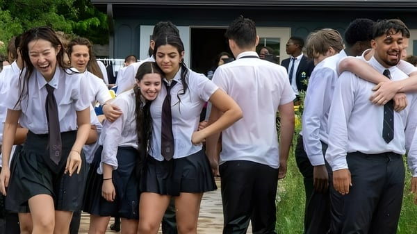 Eine Gruppe von Schülerinnen und Schülern der St. John’s-Kilmarnock School versammelt sich draußen vor einem Gebäude mit Grünfläche im Hintergrund.