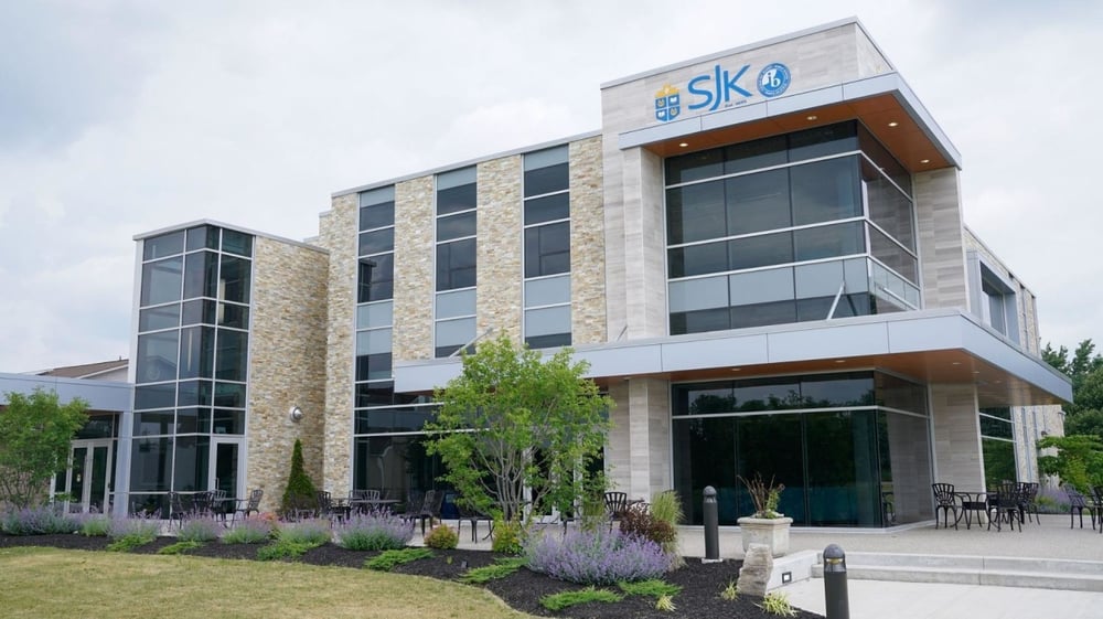 Das moderne mehrstöckige Gebäude der St. John’s-Kilmarnock School ist von Grünanlagen und Sitzbereichen umgeben.