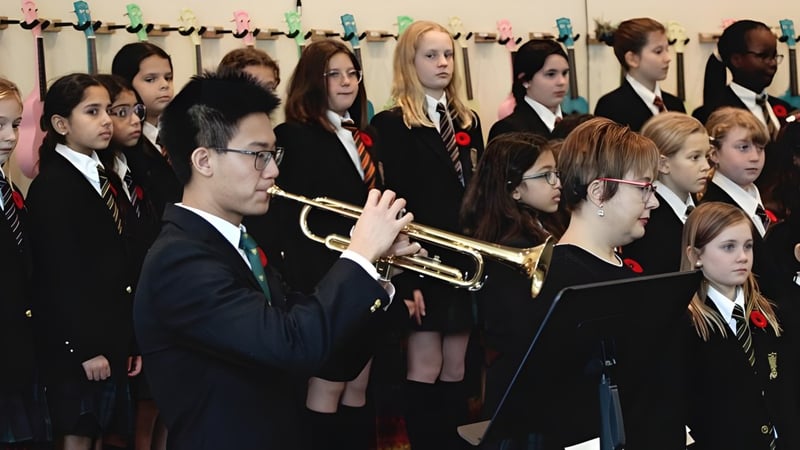Eine Gruppe Schüler der St. John’s-Ravenscourt School steht in Schuluniformen zusammen und hält Musikinstrumente.