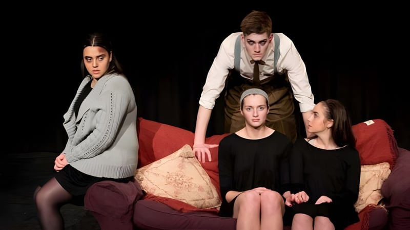 Eine Gruppe von Schülerinnen der St. John’s School sitzt auf einem roten Sofa vor dunklem Hintergrund.