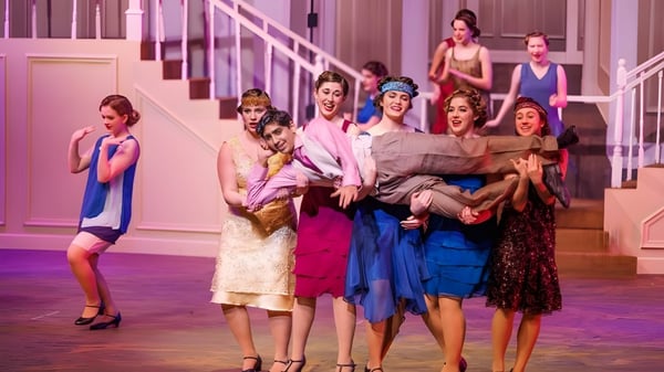 Schülerinnen der St. John's School führen eine lebhafte Aufführung auf einer Treppe durch.