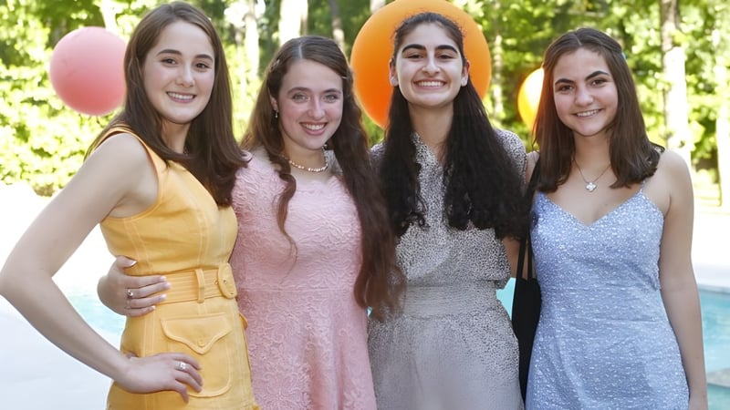 Vier Schülerinnen der St. John's School stehen zusammen in einer grünen Außenanlage.