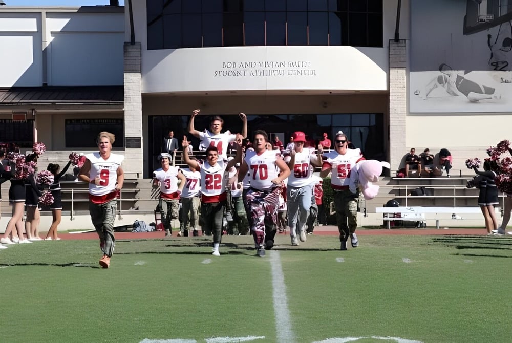 Eine Gruppe Schüler steht als Sportteam auf dem Sportplatz vor dem Gebäude der St. John's School.