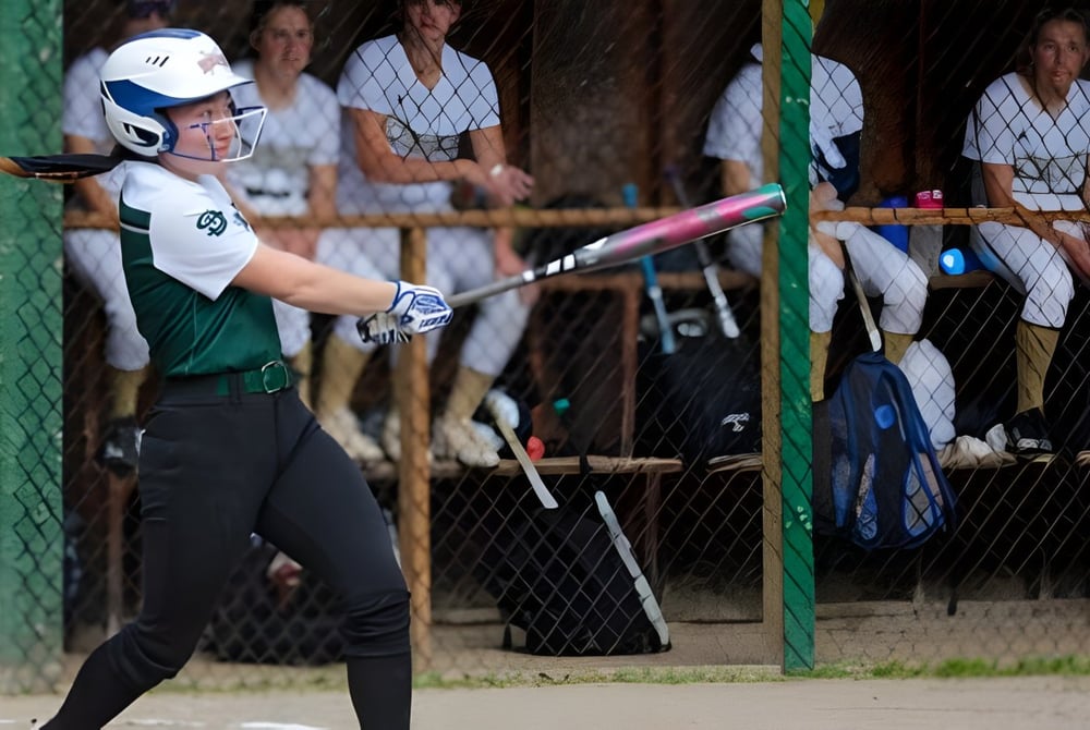 Ein Baseballspieler der St. Johnsbury Academy schlägt am Schlagmal während eines Spiels mit Zuschauern auf den Tribünen.