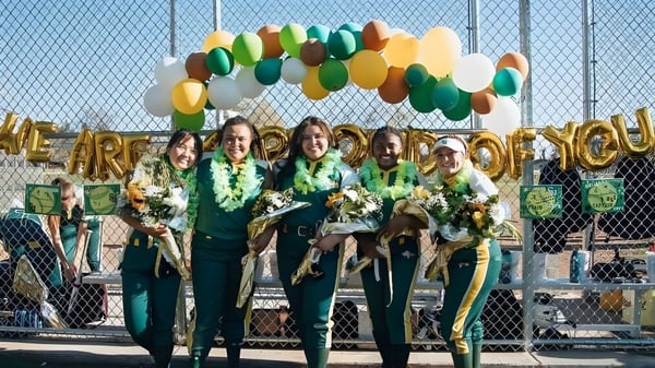 Eine Gruppe von Schülern der St. Joseph Catholic High School steht vor einem Banner mit der Aufschrift ‚We are the champions‘.