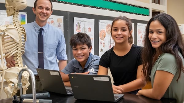 Schüler und eine Lehrkraft der St. Joseph High School arbeiten gemeinsam an einem Laptop im Klassenraum mit anatomischen Modellen.