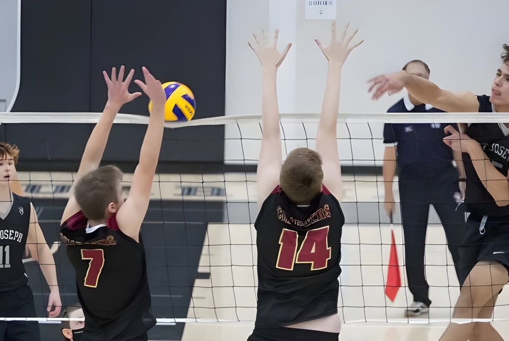 Schülerinnen und Schüler der St. Joseph High School spielen Volleyball und versuchen am Netz den Ball zu blocken.