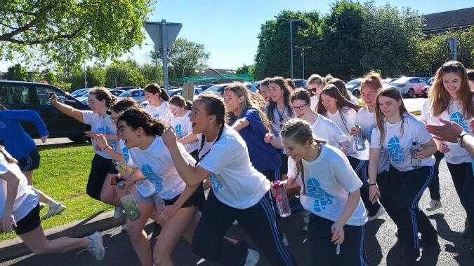 Eine Gruppe von Schülerinnen im weißen Hemd steht auf dem Außengelände der St. Joseph of Cluny School.