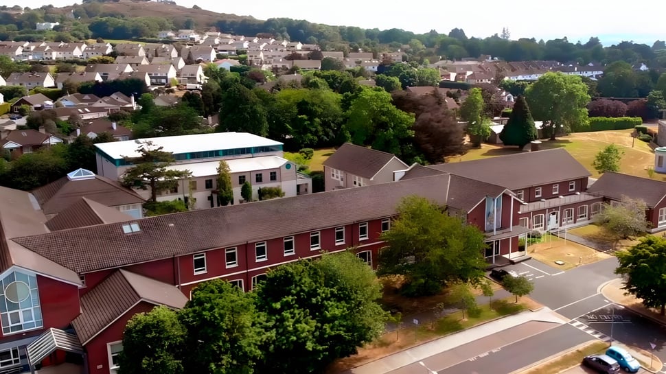 Eine idyllische Landschaft mit Hügeln und Gebäuden nahe der St. Joseph of Cluny School.