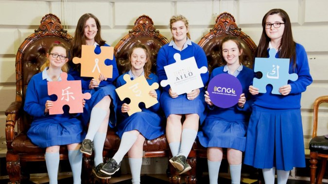 Eine Gruppe junger Schülerinnen der St. Joseph of Cluny School hält vor einem verzierten Holzstuhl Puzzleteile.