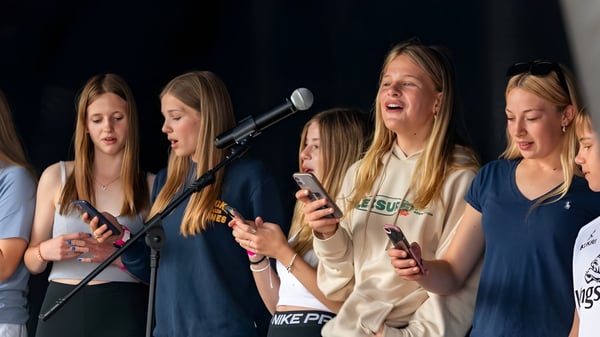 Eine Gruppe Schülerinnen des St. Joseph's College führt mit Mikrofonen auf der Bühne ein Bühnenprogramm auf.
