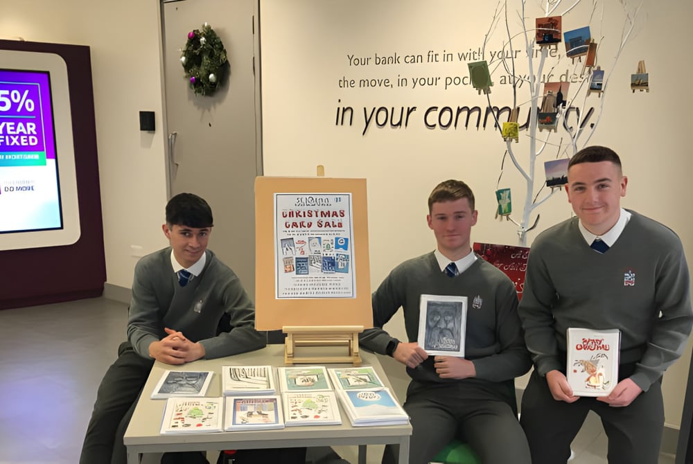 Drei Schüler in Uniform stehen hinter einem Ausstelltisch mit verschiedenen Gegenständen auf dem Campus der St. Joseph's Secondary School.