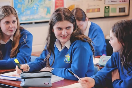 Schüler der St. Joseph’s Secondary School sitzen gemeinsam an einem Tisch und arbeiten im Klassenraum zusammen.