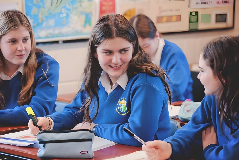 Schüler der St. Joseph’s Secondary School sitzen gemeinsam an einem Tisch und arbeiten im Klassenraum zusammen.