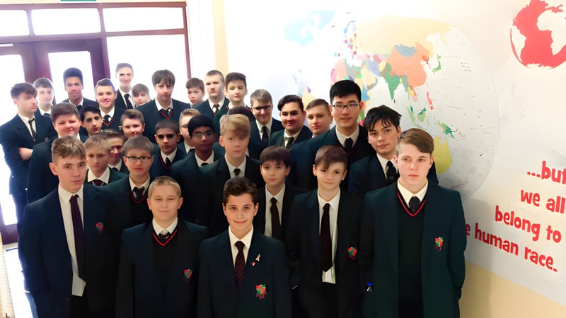Eine Gruppe Schülerinnen und Schüler der St. Joseph's Secondary School steht vor einer Weltkarte an der Wand.