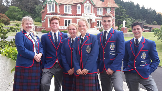 Eine Gruppe Schüler im Schuluniform steht vor dem viktorianischen Gebäude auf dem Campus von St. Kevin’s College.