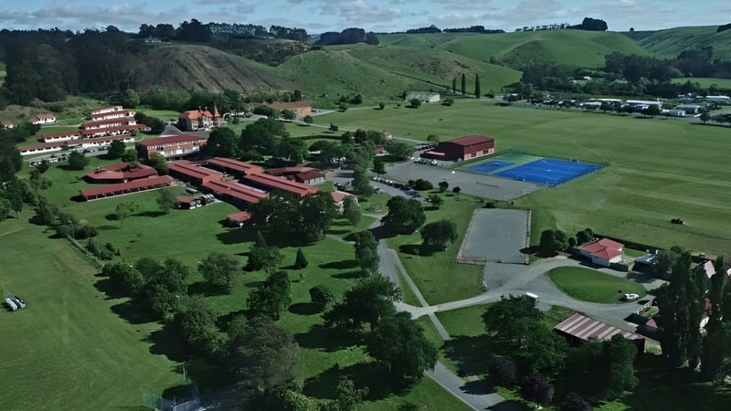 Der Tennisplatz auf dem Gelände von St. Kevin’s College ist umgeben von grünen Hügeln und roten Gebäuden.