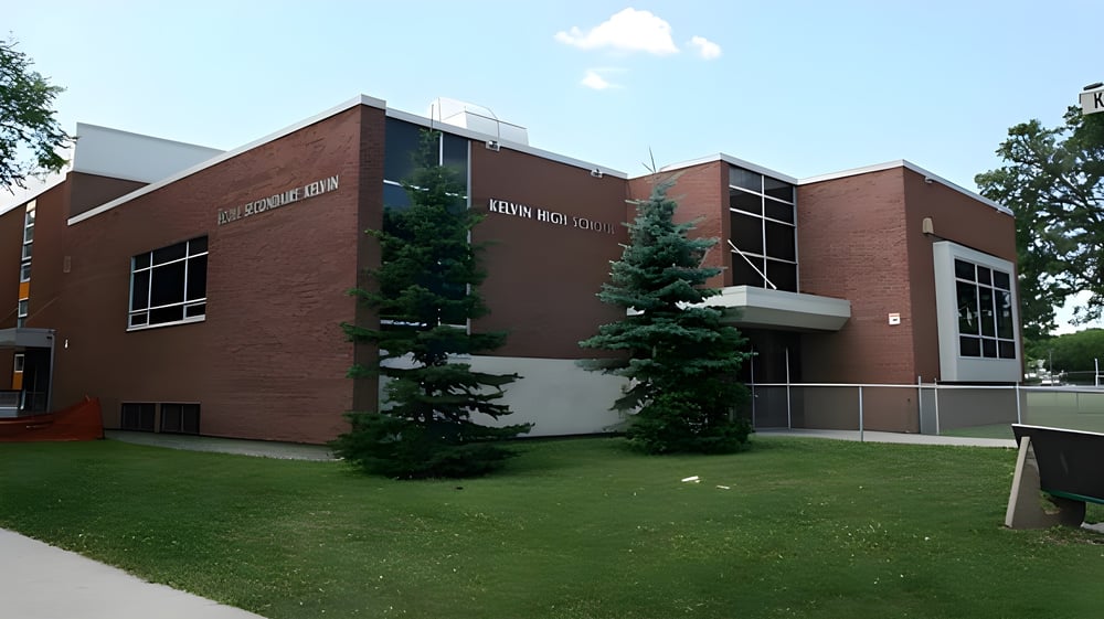 Das mehrstöckige Backsteingebäude von St. Kevin's High School ist von Rasenflächen und Bäumen umgeben.