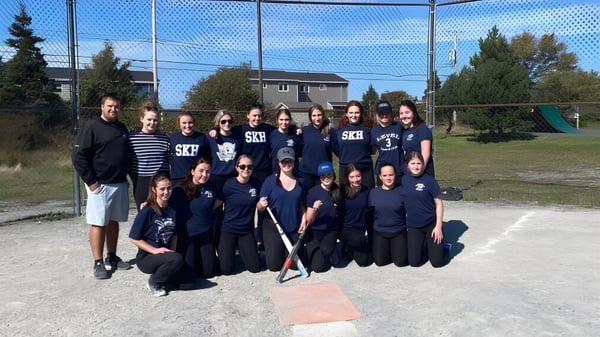 Eine Gruppe Schülerinnen und Schüler der St. Kevin's High School steht gemeinsam auf einem Sportplatz vor Gebäuden und Bäumen.