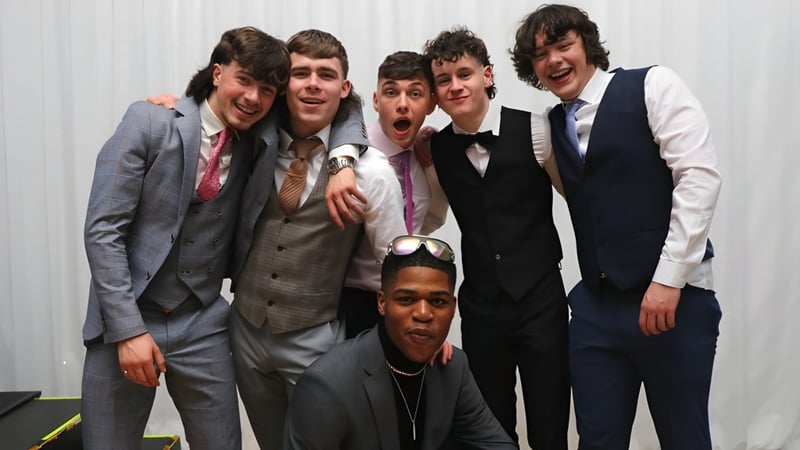 Eine Gruppe Schüler von St. Kieran’s College in formeller Kleidung posiert vor einem weißen Hintergrund, einige machen lustige Gesichter.