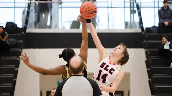 Ein Basketballspieler in rotem Trikot springt zum Wurf beim Spiel auf dem Campus des St. Lawrence College.