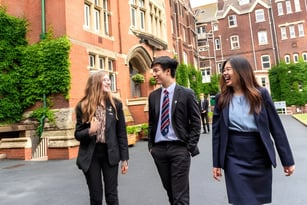 Drei Schüler gehen gemeinsam auf einem Campusweg am St. Lawrence College vorbei an mit Efeu bewachsenen Backsteingebäuden.