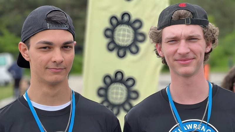Zwei Schüler stehen vor einem farbenfrohen Wandbild mit Blumenmustern auf dem Gelände der St. Lawrence Secondary School.