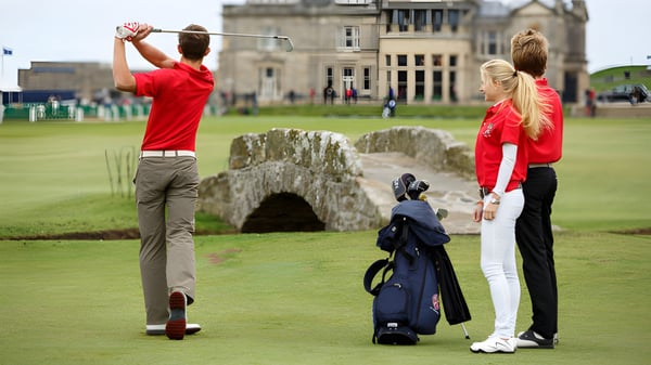 Zwei Schüler der St. Leonards School spielen Golf auf einem Rasen vor einem historischen Steingebäude.