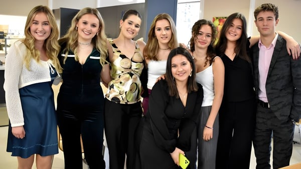 Eine Gruppe Schülerinnen und Schüler steht zusammen vor einem neutralen Hintergrund auf dem Gelände der St. Leonards School.