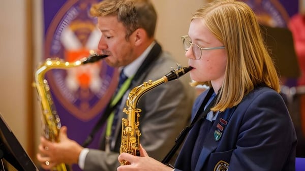 Zwei Schülerinnen und Schüler spielen Saxophon auf der Bühne der St. Leonards School vor einem lila Hintergrund.