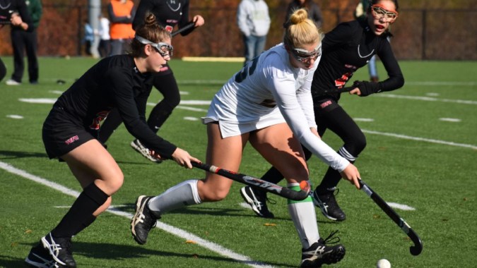 Schüler des St. Leo’s College spielen ein Feldhockeyspiel auf einem grünen Spielfeld.